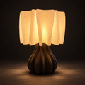 A modern table lamp with a glowing warm white pleated shade and a ribbed dark brown base, set against a dark studio background.