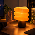 Three-quarter view of the Kiro Aurelle table lamp showing its layered triangular shade, beige finish and brown base.